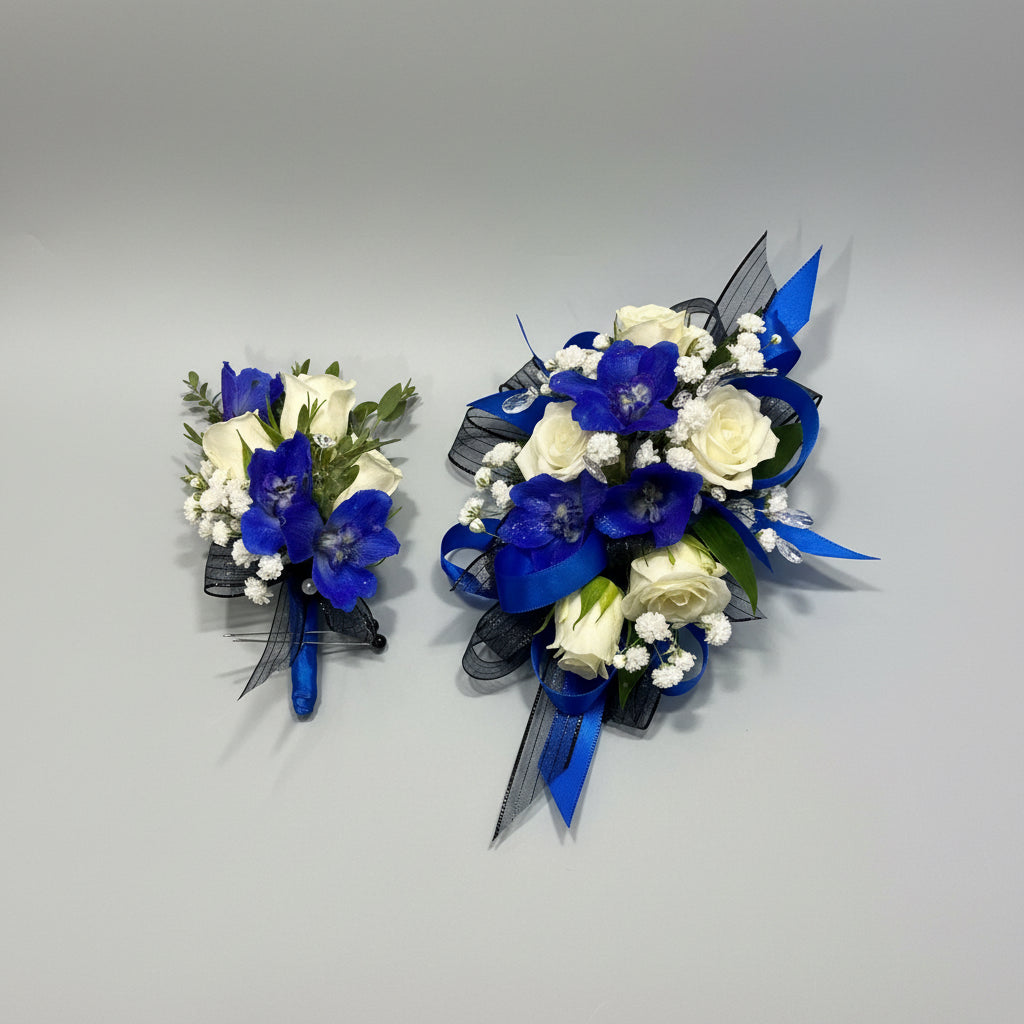 A floral wristlet and matching boutonniere set featuring white roses, blue columbine, baby's breath, and blue ribbons on light blue tissue paper.